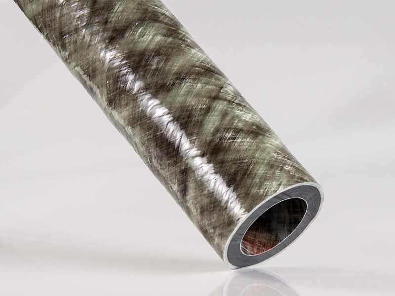 Image shows the one custom composite tube with the end placed on a white ground. The tube has carbon fiber interior layers and exterior fiberglass layers. The surface has a filament wound texture and glossy finish.